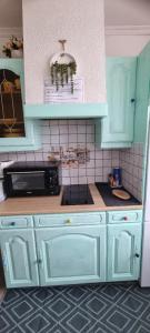 cocina con armarios azules y microondas en Sympa Appartement avec 2 chambres séparées, en Persan