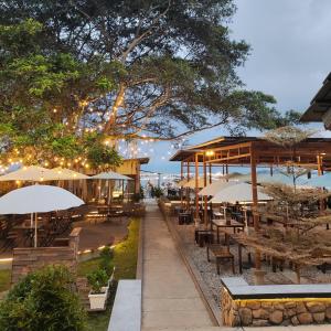 Damar Toba في باليج: مطعم به طاولات ومظلات على الشاطئ