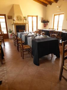 una sala da pranzo con tavoli, sedie e camino di Tenute Testoni Agriturismo e B&B a Bassacutena