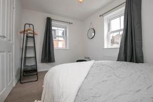 a bedroom with a white bed and two windows at Cozy House in The Heart of Colchester in Colchester