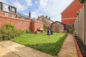 a backyard with a grassy yard next to a brick building at Cozy House in The Heart of Colchester in Colchester