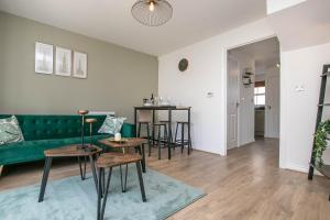 a living room with a green couch and tables at Cozy House in The Heart of Colchester in Colchester