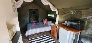 a bedroom in a tent with a bed and a microwave at Tava Lingwe Game Lodge & Wedding Venue in Parys