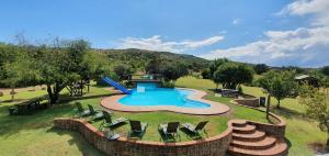 an outdoor swimming pool with chairs and a slide at Tava Lingwe Game Lodge & Wedding Venue in Parys