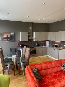 a living room with a red couch and a kitchen at Halvard Apartments at Castletown in Castletown