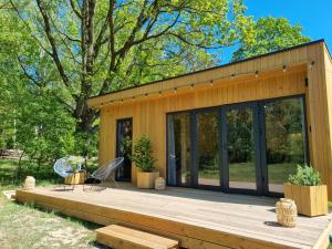 a tiny house with a deck and glass doors at Ale Miejscówka! Całoroczny domek nad jeziorem in Lucień