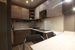 a kitchen with wooden cabinets and a sink and two chairs at Apartament w sercu Karkonoszy in Jelenia Góra