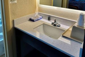 un bancone del bagno con lavandino e specchio di Days Inn by Wyndham Charlotte Northlake a Charlotte
