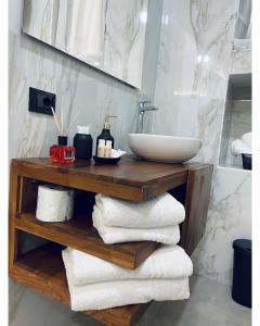 ein Badezimmer mit einem Waschbecken und Handtüchern auf einem Holzregal in der Unterkunft Suite Whiteflower in Bari