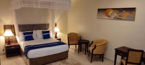 a hotel room with a bed and a table and chairs at Koki Hotel in Kampala