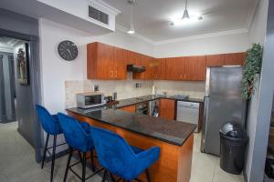 a kitchen with a counter and blue bar stools at Stay at The Point - Arabian Affair in Durban