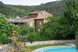 une grande maison en pierre avec une piscine dans un jardin dans l'établissement Mas Suéjol, à Anduze