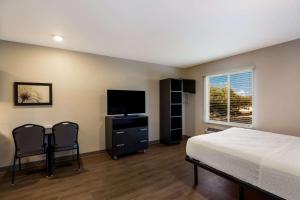 a bedroom with a bed and a flat screen tv at WoodSpring Suites Orlando West - Clermont in Clermont
