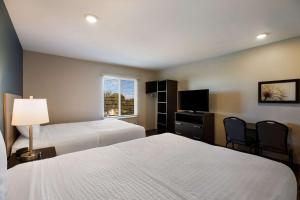 una camera d'albergo con due letti e una televisione di WoodSpring Suites Orlando West - Clermont a Clermont