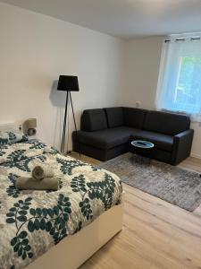 um quarto com uma cama e um sofá preto em Apartment VBK Osijek em Osijek