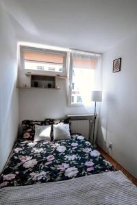 a small bedroom with a bed with a floral blanket at Przytulne mieszkanie w centrum in Warsaw