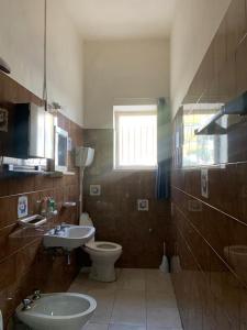 uma casa de banho com um lavatório, um WC e uma janela. em Rustic cottage in Montalbano jonico em Montalbano Ionico