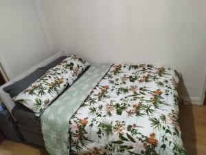 a bed with a floral comforter and two pillows on it at Nice Studio Flat in Edmonton, North London in Edmonton