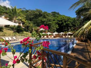 a pool at a resort with pink flowers on a fence at Bangalô em Ilhabela/Yacamim in Ilhabela