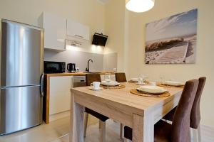 a kitchen with a table and a stainless steel refrigerator at Bryza - apartament w Sopocie by Grand Apartments in Sopot