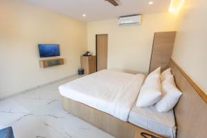 1 dormitorio con 1 cama y TV en la pared en Pushp Vatika Resort & Lawns en Navi Mumbai