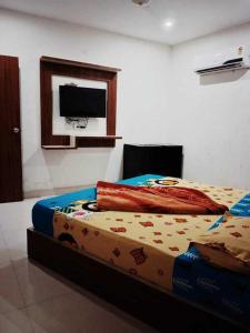 uma cama num quarto com uma televisão na parede em POP Hotel H5 em Kurukshetra