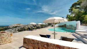a pool with chairs and umbrellas on a patio at Monte Sarago Villas in Ostuni