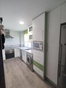 una cocina con lavadora y una persona parada en ella en Apartamento luminoso con jardín, en La Zubia