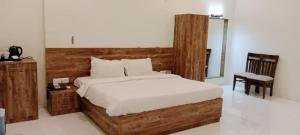 a bedroom with a large bed with a wooden headboard at Pushp Vatika Resort & Lawns in Navi Mumbai