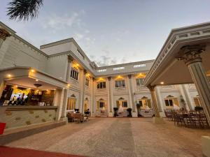 a large white building with a courtyard with tables and chairs at El Palacio Hotel & Resort in Cavite