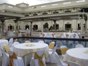 a banquet hall with white tables and white chairs at El Palacio Hotel & Resort in Cavite