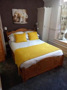 a bedroom with a bed with a yellow blanket on it at Virginia Cottage Guest House in Bowness-on-Windermere