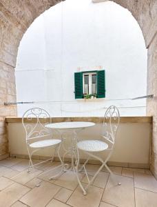 a table and chairs on a patio with a window at Nonno Pasquale house in Locorotondo