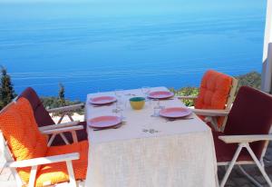 a table with plates and wine glasses sitting on a balcony at Porto Katsiki Blu in Athani