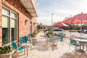 un patio con sillas, mesas y una sombrilla en TownePlace Suites by Marriott Charlotte Mooresville, en Mooresville