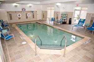 a large swimming pool with blue chairs in a building at TownePlace Suites by Marriott Charlotte Mooresville in Mooresville