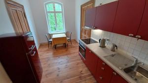 a kitchen with red cabinets and a table and a window at "Parkwohnung" im Kunstgut Krahne in Krahne