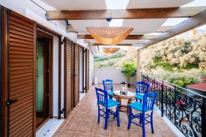 a patio with blue chairs and a table on a balcony at Casa di Cuore - Beachfront in Argasi