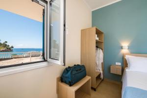 a bedroom with a bed and a window with a view of the ocean at Pargabella apartments in Parga