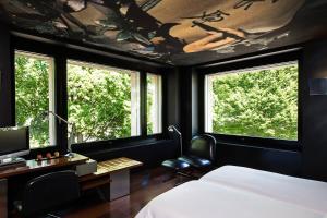 a bedroom with a bed and a desk and windows at The Hotel Lucerne, Autograph Collection in Lucerne