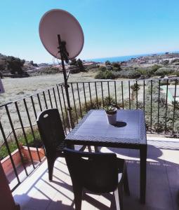 een tafel en stoelen op een balkon met uitzicht op de oceaan bij Appartamento Rosariomaria in Realmonte