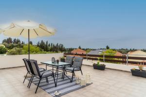 a patio with a table and chairs and an umbrella at Inalia Modern House in Lefkimmi