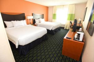 a hotel room with two beds and a desk with a television at Fairfield Inn Topeka in Topeka