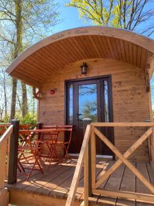 a small wooden cabin with a deck with a table at Les Roulottes de l Herm Piscine Jacuzzi Perigord in Rouffignac Saint-Cernin