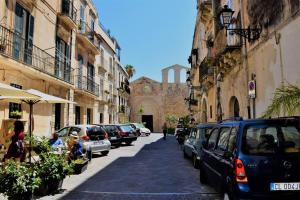 a street with cars parked on the side of a building at The little house of Ely in Siracusa