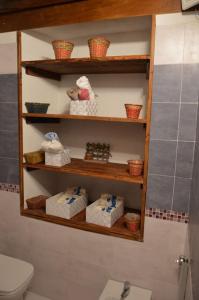 a bathroom with a toilet and shelves with towels at The little house of Ely in Siracusa