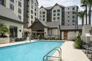 a pool at a hotel with chairs and buildings at Residence Inn By Marriott Jacksonville-Mayo Clinic Area in Jacksonville