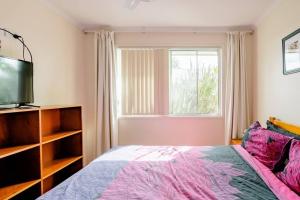 Yandina的住宿－Cosy Home in Yandina，一间卧室设有一张床、一台电视和一个窗口。