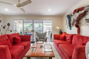 a living room with red couches and a wooden table at Cosy Home in Yandina in Yandina