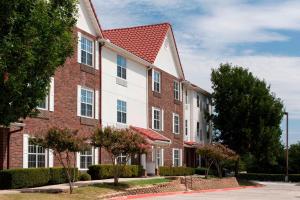 a large brick building with a red roof at TownePlace Suites Dallas Las Colinas in Irving